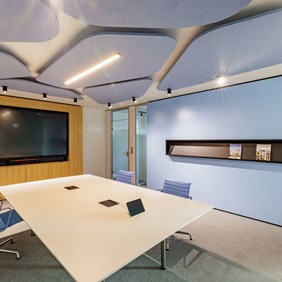 Painéis acústicos azuis claros combinados com projectores CENTRIQ no teto de uma sala de reuniões - iluminação acústica para uma acústica óptima da sala durante as reuniões