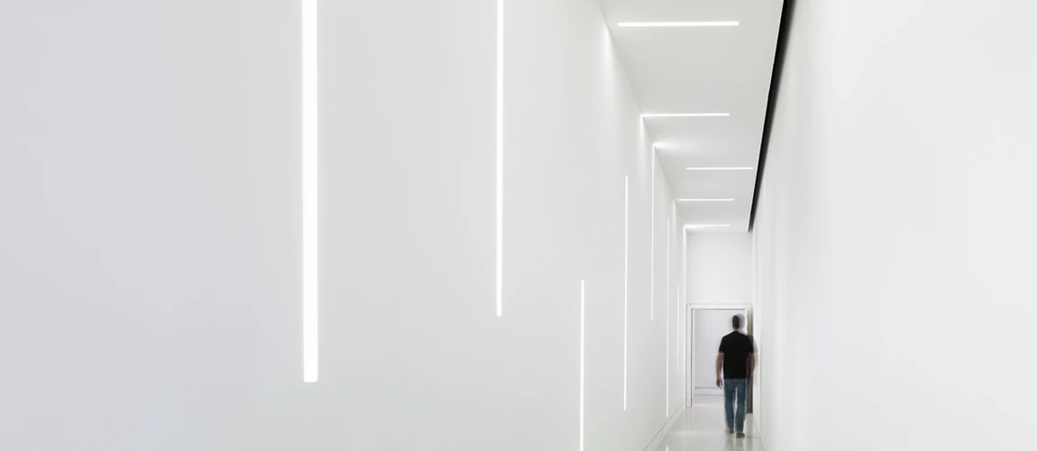 Linhas de luz LED subtis num corredor. A iluminação é montada na Parede e no teto e ligada por um conetor.