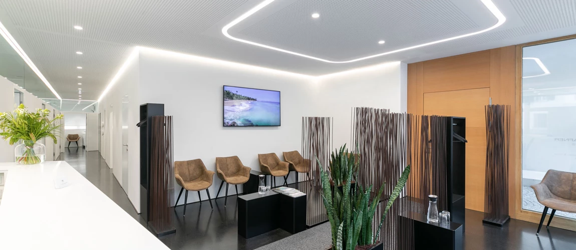 Modern ceiling lighting provides uniform and friendly illumination of the waiting room in a doctor's office.