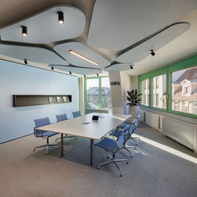 Projectores CENTRIQ integrados em grandes painéis acústicos num azul discreto numa sala de reuniões - iluminação de escritório combinada com absorção sonora