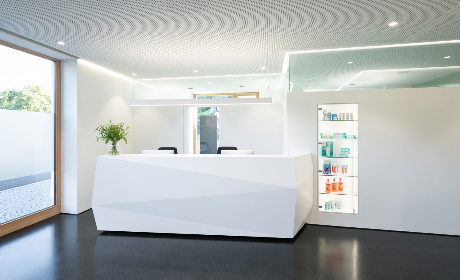 La iluminación de techo, brillante y moderna, en la zona de recepción de un consultorio médico crea un ambiente agradable para pacientes y visitantes.