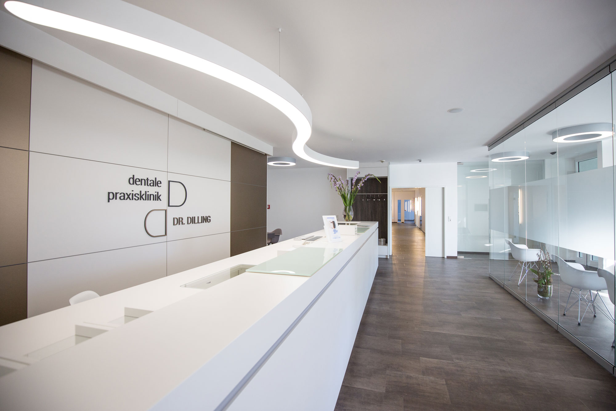 Una gran lámpara de techo blanca proporciona una iluminación brillante y acogedora en la zona de recepción de un moderno consultorio médico.