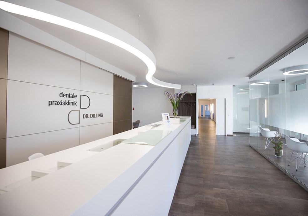 A large, white ceiling light provides bright and inviting lighting in the reception area of a modern doctor's office.